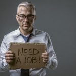Broke jobless businessman holding a cardboard sign