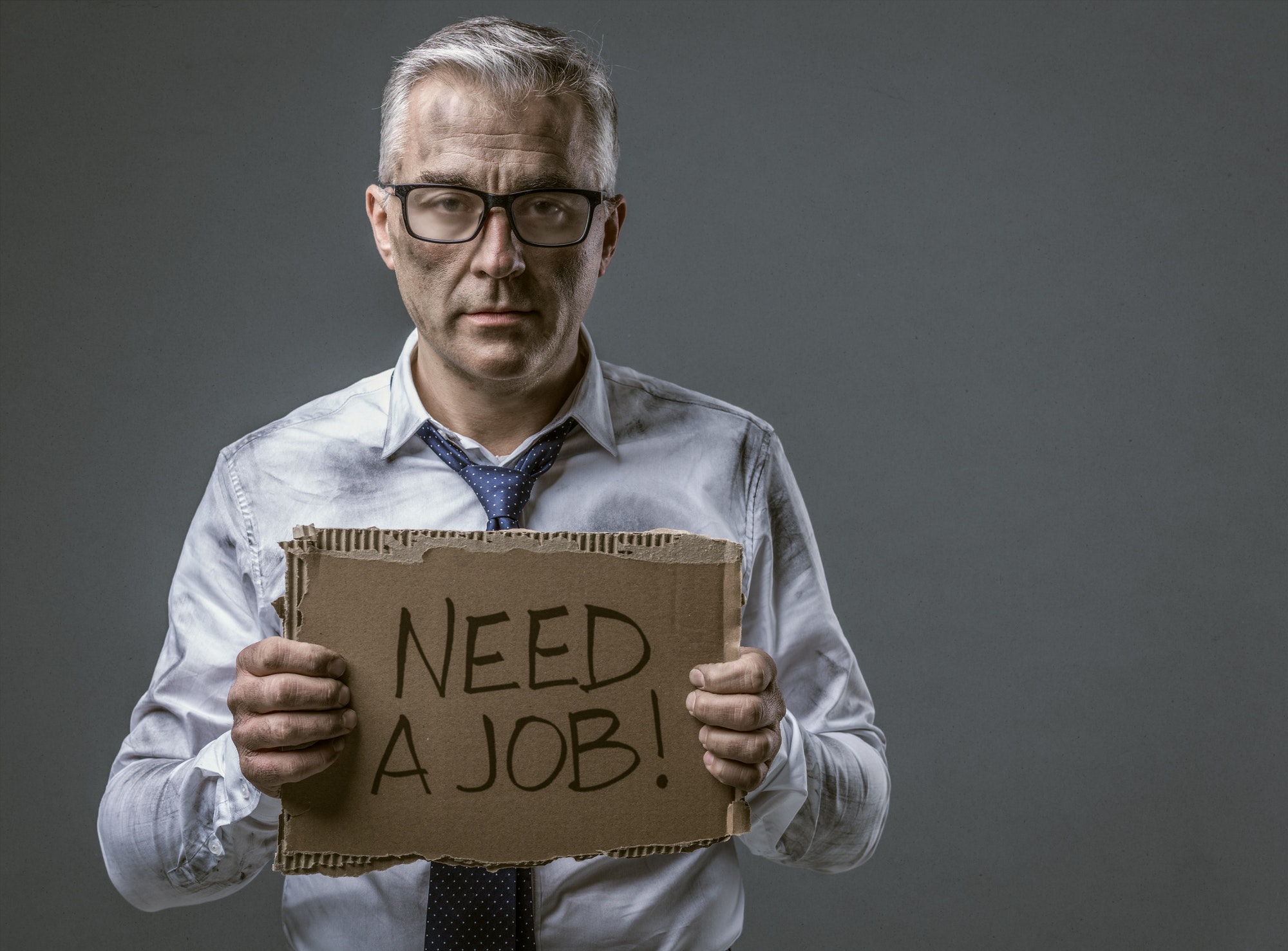 Broke jobless businessman holding a cardboard sign