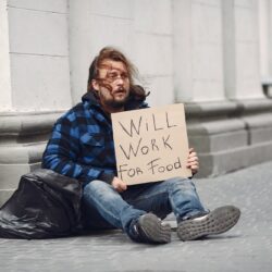 Homeless in a city. Man asking for food. Man with a tablet