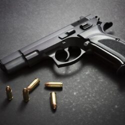 Handgun with ammunition on black background in bright light