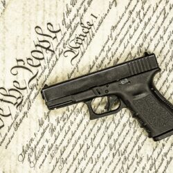 A handgun symbolizing gun rights while framed against the United States constitution.