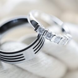 Two silver platinum and titanium diamond wedding rings on white rope background