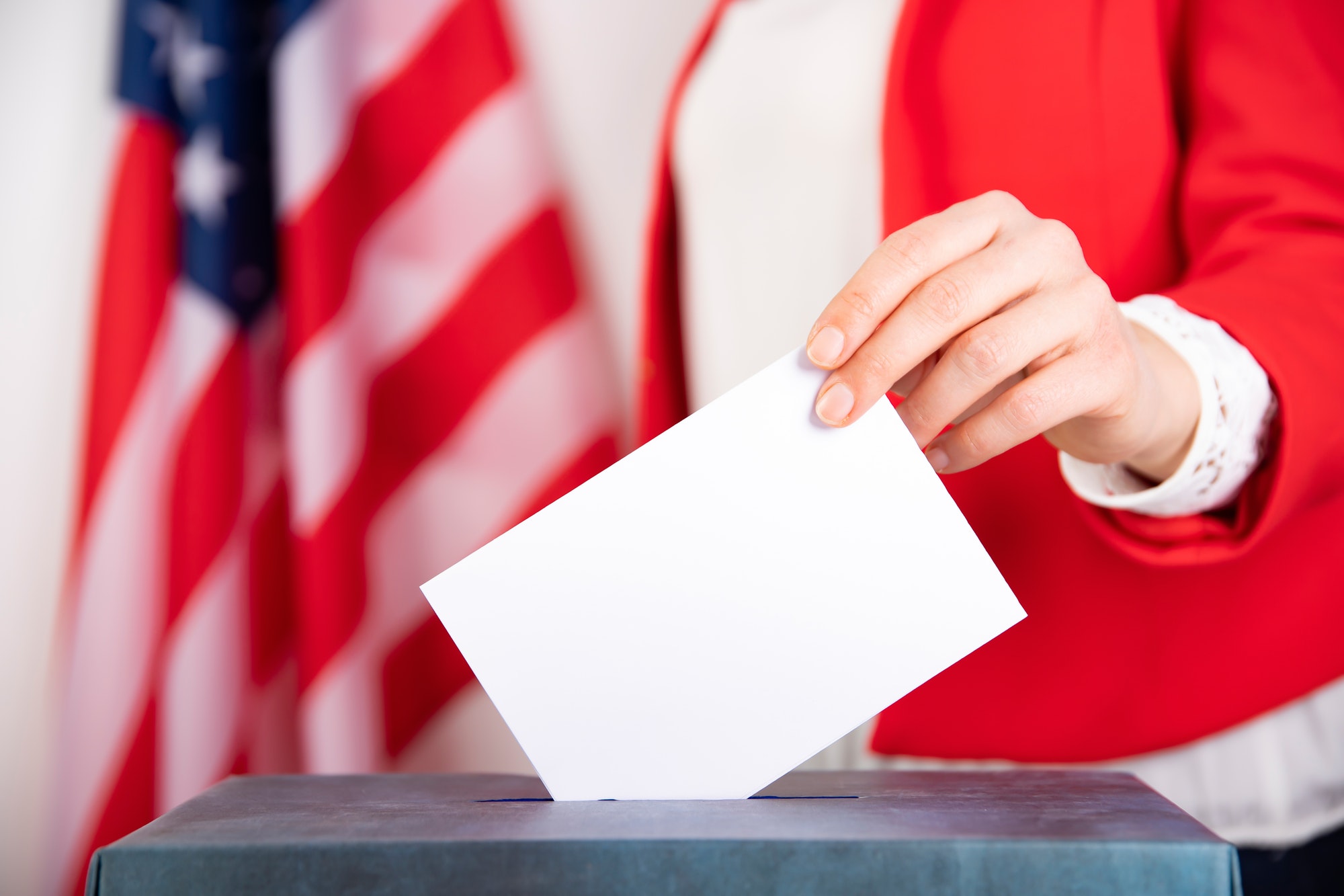 American voter putting ballot into voting box.