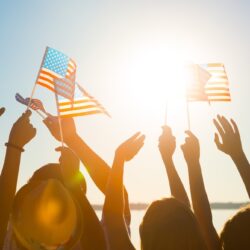 American flag. Fans meet idol. Crowd of waving American flags. Party on the waterfront. Concert in the resort town. Patriots of their country.