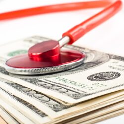 dollars cosulted with a red stethoscope close-up on white background