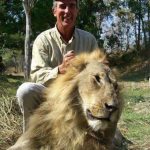 Sandy Stimpson from Mobile, AL posing with a dead lion he killed while hunting