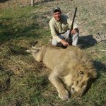 Sandy Stimpson from Mobile, AL posing with a dead lion he killed while hunting